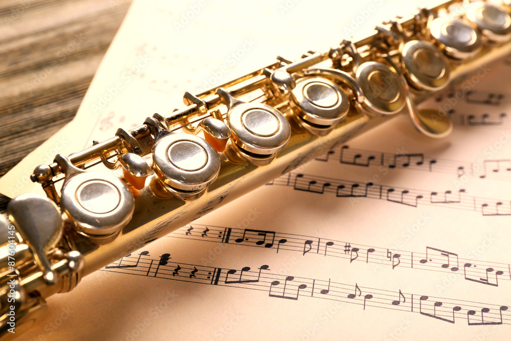 Obraz premium Silver flute with music notes on wooden table close up