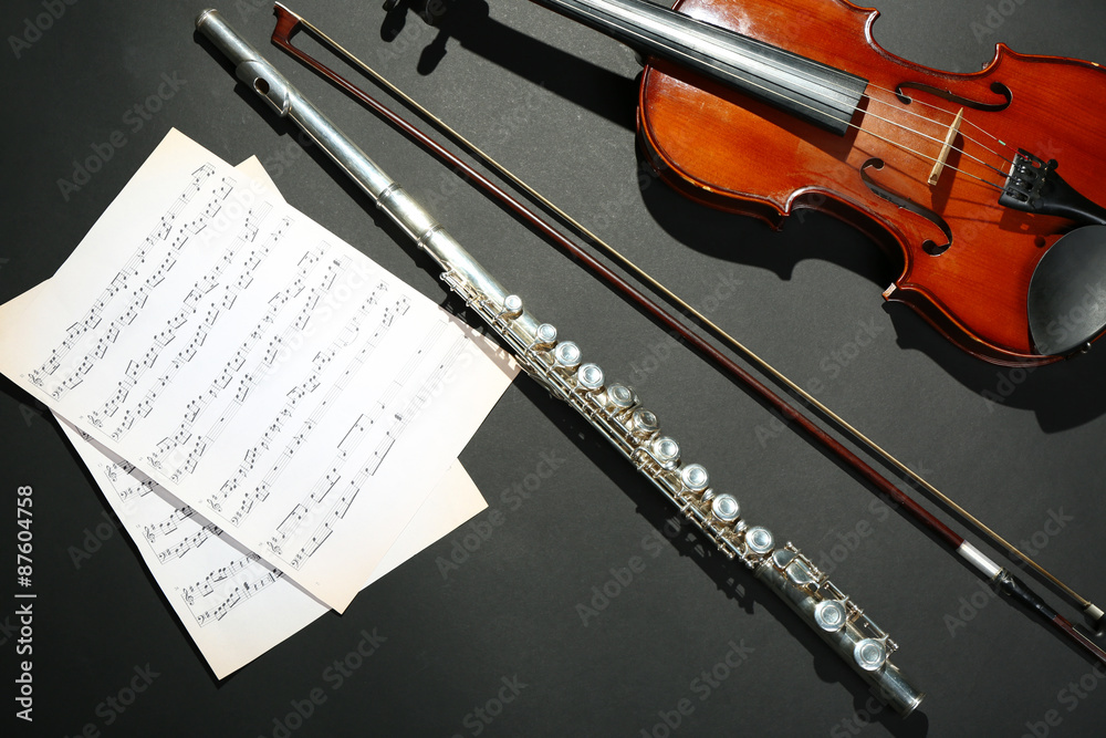 Fototapeta premium Violin and flute with music notes on dark background