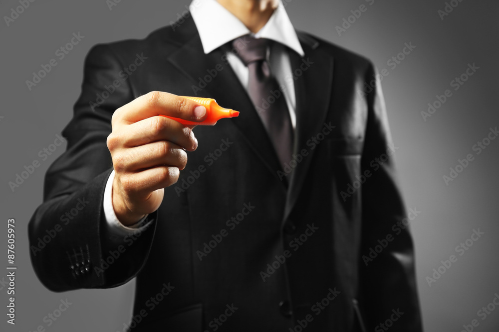 Fototapeta premium Businessman holding marker on gray background