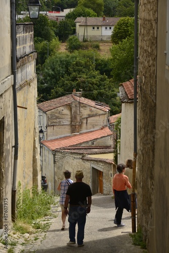 Touristes descendant une ruelle en forte pente depuis la haute ville de Saintes 