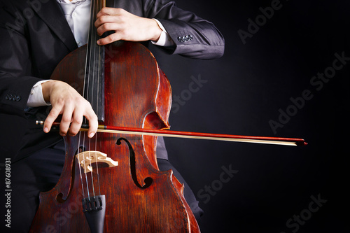Obraz na plátne Man playing on cello on dark background