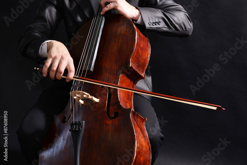 Man playing on cello on dark background