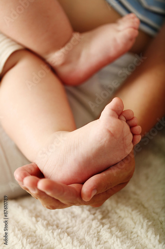 Adult hands holding baby feet, closeup