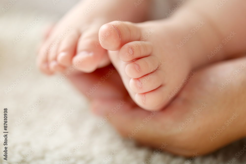 Adult hands holding baby feet, closeup Adult hands holding baby feet, closeup