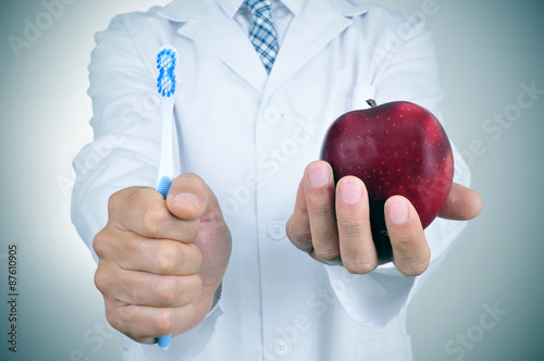 a dentist showing a toothbrush and an apple photo