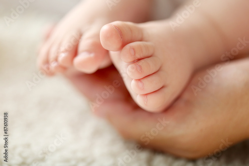 Adult hands holding baby feet, closeup