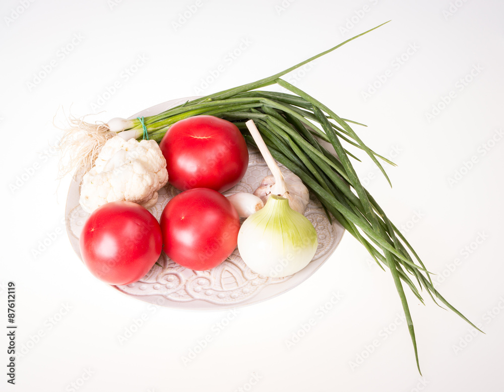 Tomatoes, garlic, onion and chive on plate isolated