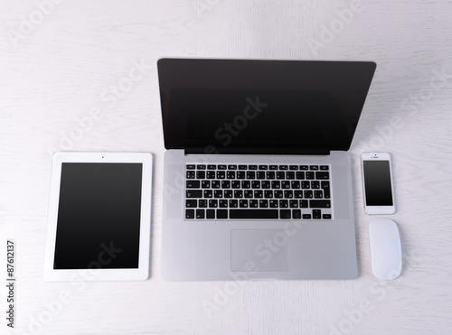 Laptop, mouse, tablet and mobile phone on white table, top view