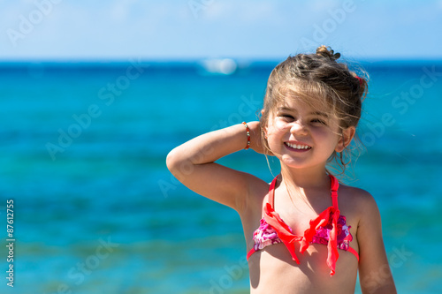 Happy smiling little girl playing at sea, blue sea background