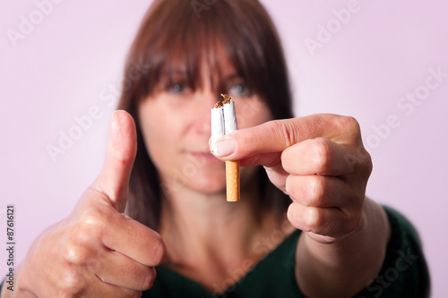 Frau hält zerbrochen Zigarette und den Daumen nach oben dazu