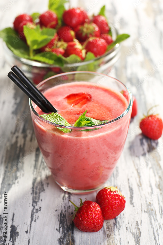 Glass of milkshake with strawberries on wooden table close up Glass of milkshake with strawberries on wooden table close up