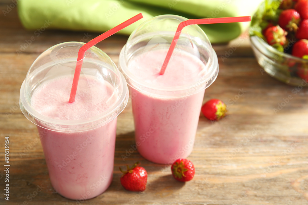Plastic cups of milkshake with strawberries on table close up Plastic cups of milkshake with strawberries on table close up