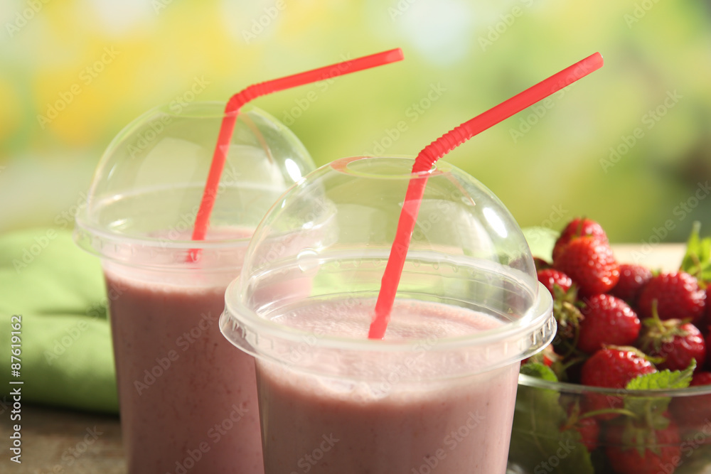 Glasses of milkshake with strawberries on bright background Glasses of milkshake with strawberries on bright background