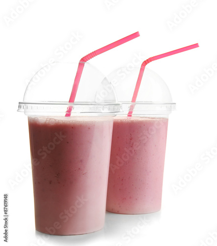 Plastic cups of milkshake with strawberries isolated on white