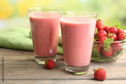 Glasses of milkshake with strawberries on table close up