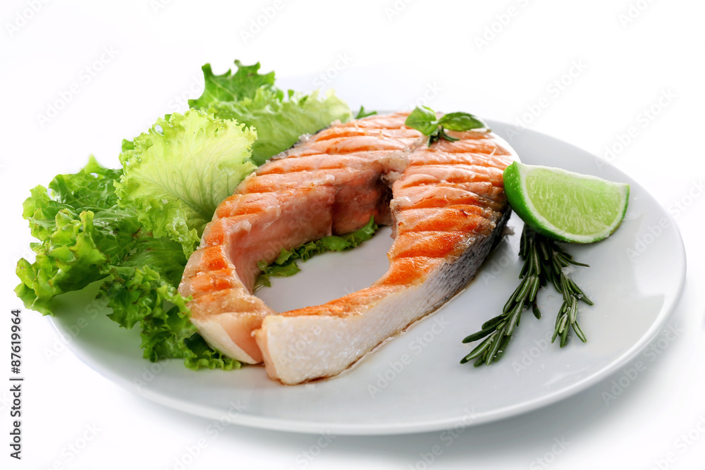 Tasty grilled salmon with lime and greens on plate close up Tasty grilled salmon with lime and greens on plate close up
