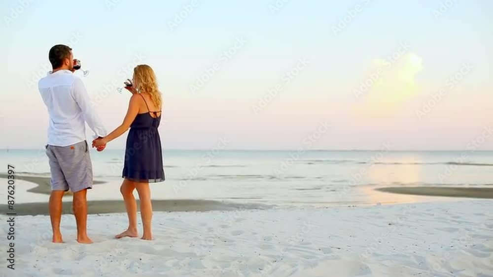 Young couple looks at the sunset and raises their wine glasses in a toast Young couple looks at the sunset and raises their wine glasses in a toast