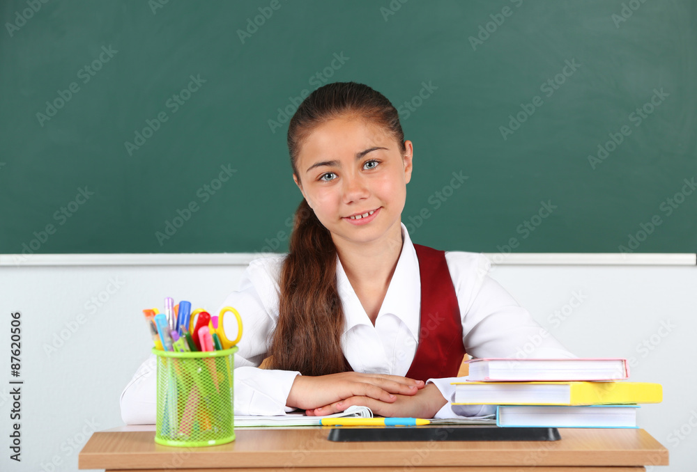 Beautiful little schoolgirl in classroom near blackboard Beautiful little schoolgirl in classroom near blackboard