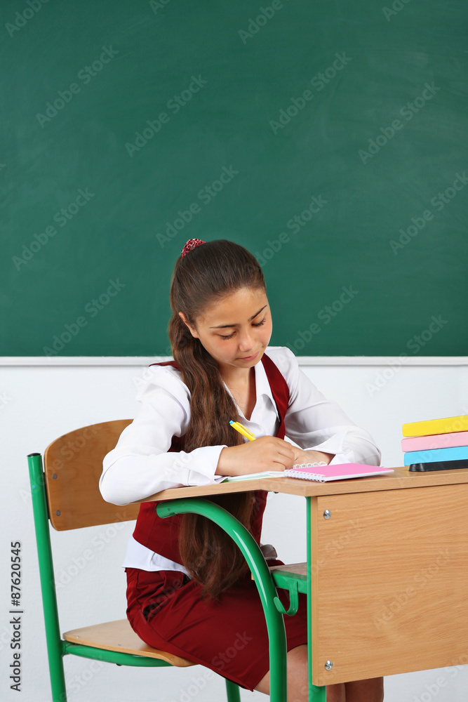 Beautiful little schoolgirl in classroom near blackboard Beautiful little schoolgirl in classroom near blackboard