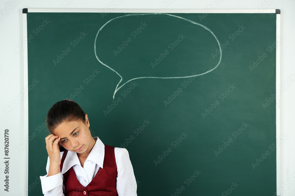 Beautiful little girl standing near blackboard