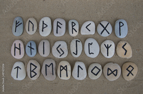 Runic alphabet on carved stones over the sand  photo