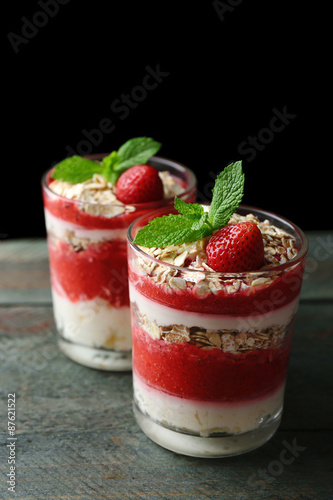 Dessert with fresh strawberry  cream and granola  on wooden table  on dark background