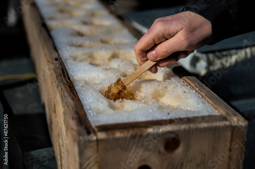 Fotografiet Hand picking maple sugar on snow