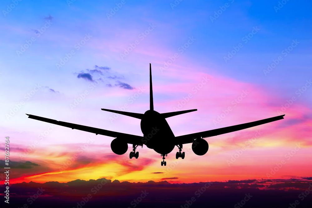 Silhouetted commercial airplane flying at sunset Silhouetted commercial airplane flying at sunset