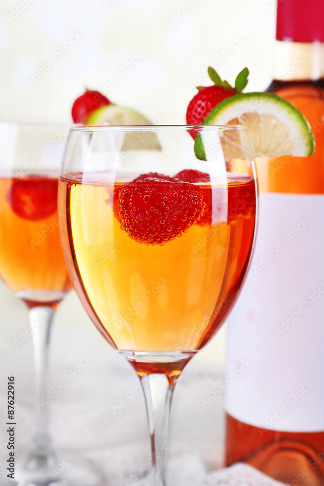 Glasses of wine with strawberries and slice of lime on light background Glasses of wine with strawberries and slice of lime on light background