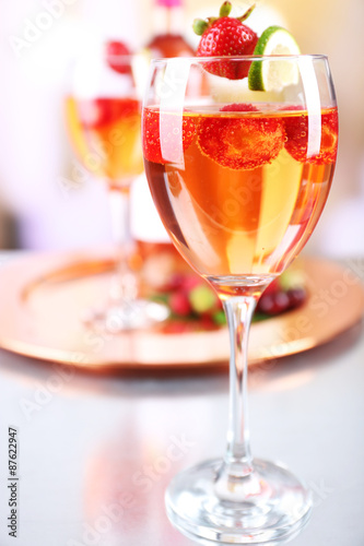 Glasses of wine with strawberries and lime on blurred background