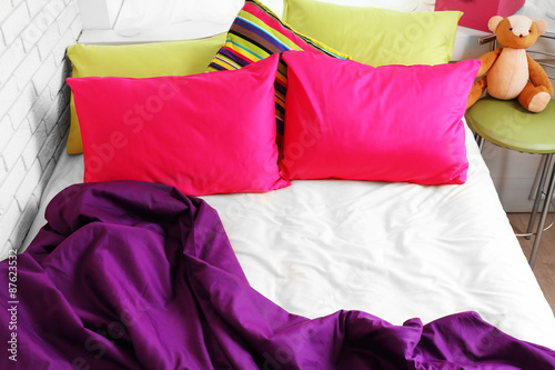 Comfortable bed with colorful pillows in bedroom © Africa Studio
