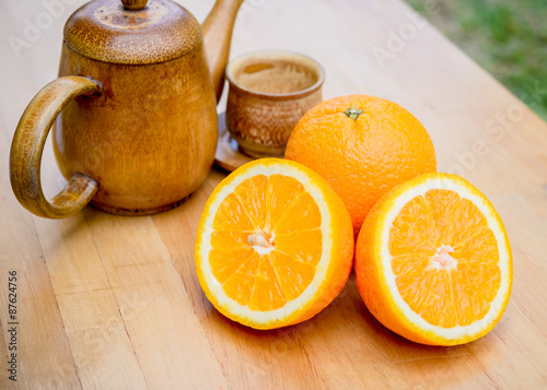 Slice of orange and wooden vase on wooden table.