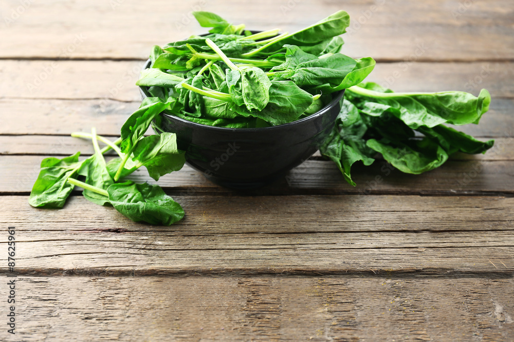 Bowl of fresh spinach leaves on wooden background Bowl of fresh spinach leaves on wooden background