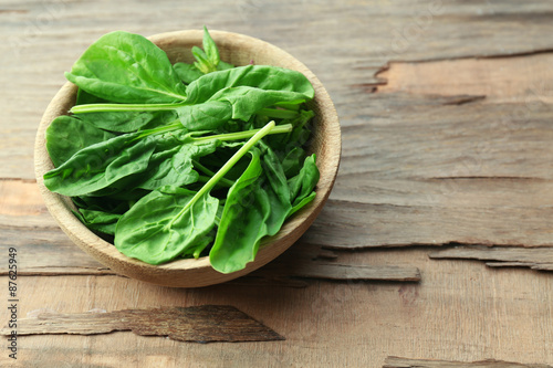 Bowl of fresh spinach leaves on wooden background