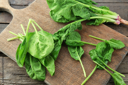 Fresh spinach leaves on wooden cutting board, closeup