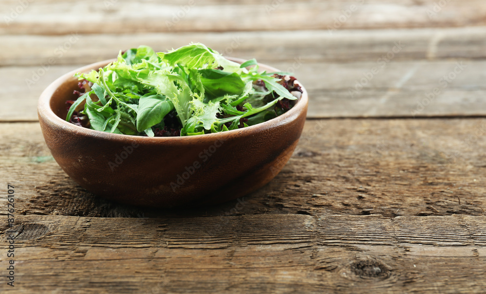 Bowl of mixed green salad on wooden background Bowl of mixed green salad on wooden background