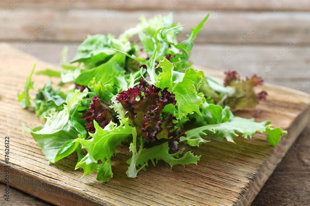 Mixed green salad on wooden cutting board, closeup Mixed green salad on wooden cutting board, closeup