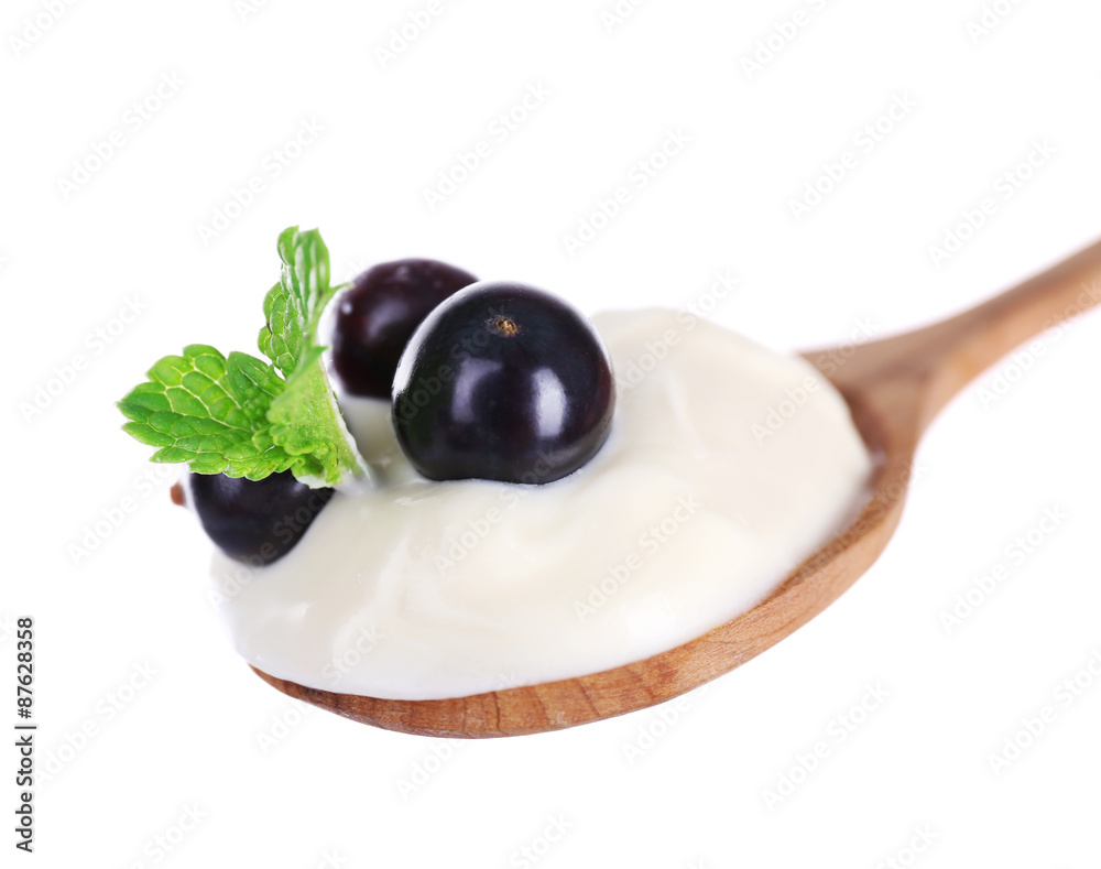 Fototapeta premium Delicious yogurt in spoon with blackcurrants and mint isolated on white