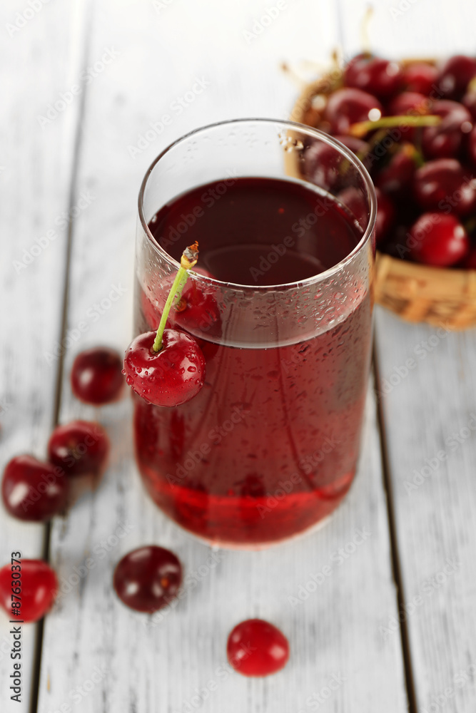 Glass of fresh juice with cherries on wooden table close up Glass of fresh juice with cherries on wooden table close up