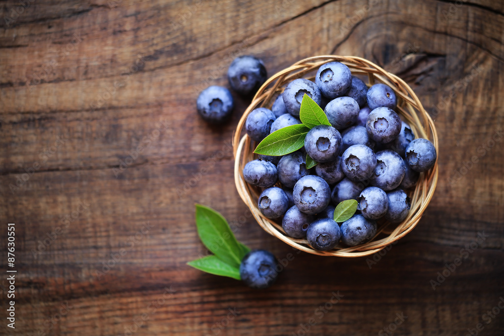 Fresh ripe garden blueberries in a wicker bowl on dark rustic wooden table. with copy space for your text - obrazy, fototapety, plakaty 