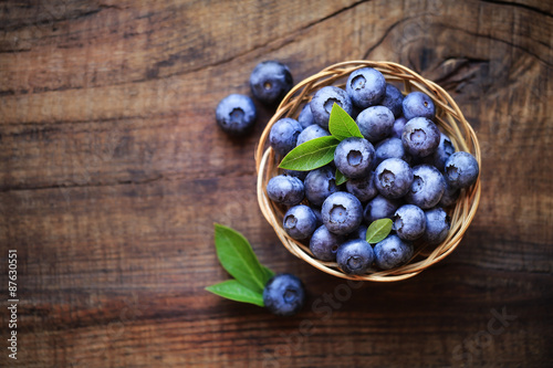 Fotografiet Fresh ripe garden blueberries in a wicker bowl on dark rustic wooden table