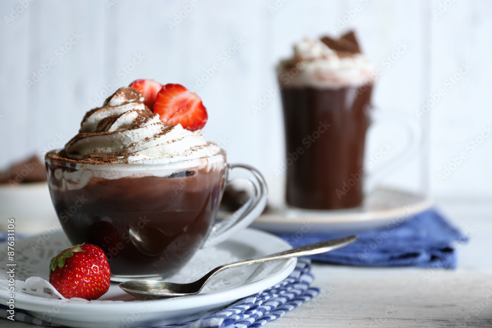 Cups of coffee with cream and fresh strawberry on color wooden background