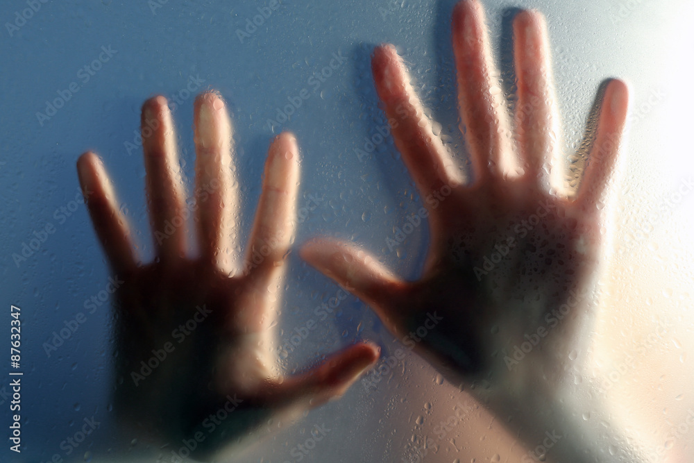 Female hands behind  wet glass, close-up