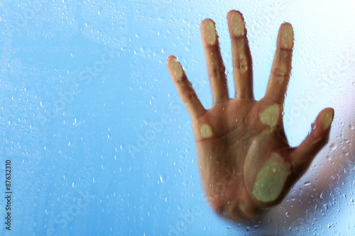 Female hand behind wet glass, close-up