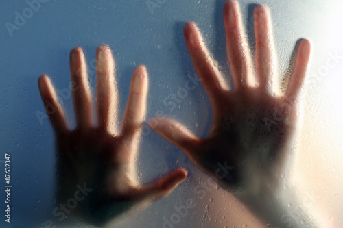 Female hands behind wet glass, close-up