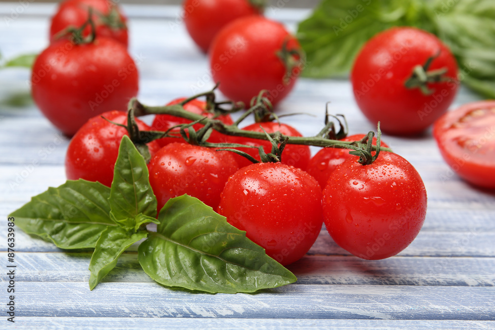 Fresh tomatoes with basil on wooden table close up Fresh tomatoes with basil on wooden table close up