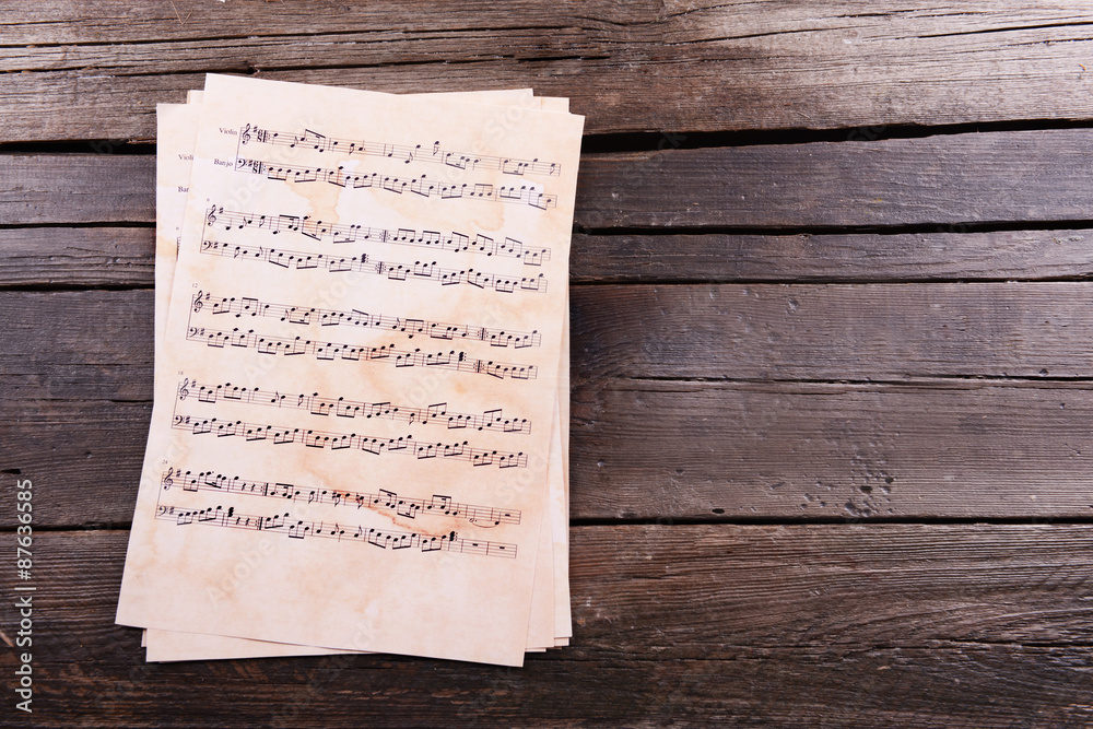 Naklejka premium Music sheets on wooden background