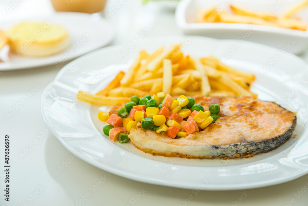 Grilled salmon steak meal served with salad and French fries Grilled salmon steak meal served with salad and French fries