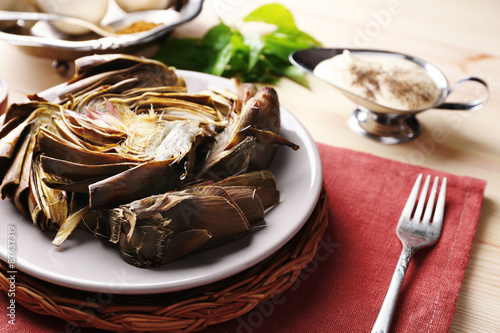 Roasted artichokes on plate, on color wooden background