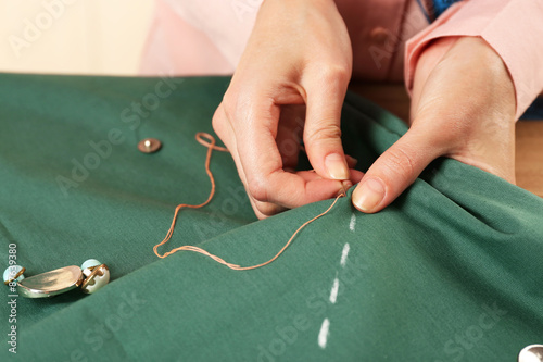 Closeup hands of seamstress at work with cloth fabric